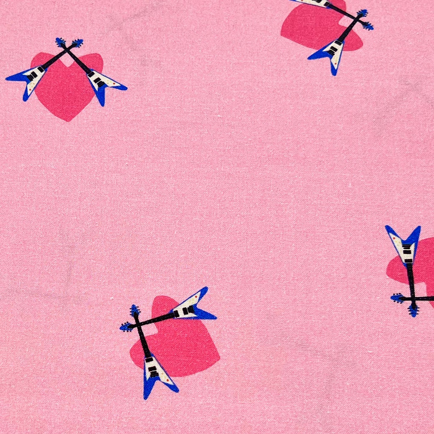 Tessuto fantasia con chitarre elettriche su fondo rosa