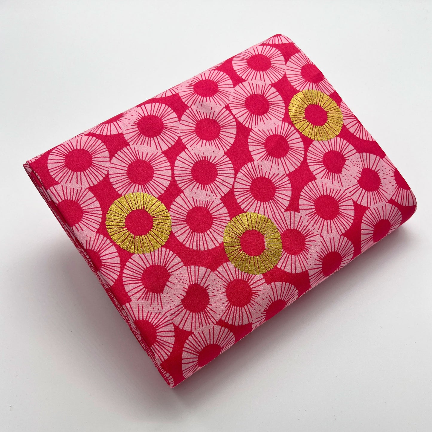 Tessuto a sfondo rosa con fantasia geometrica e dettagli oro metallizzati
