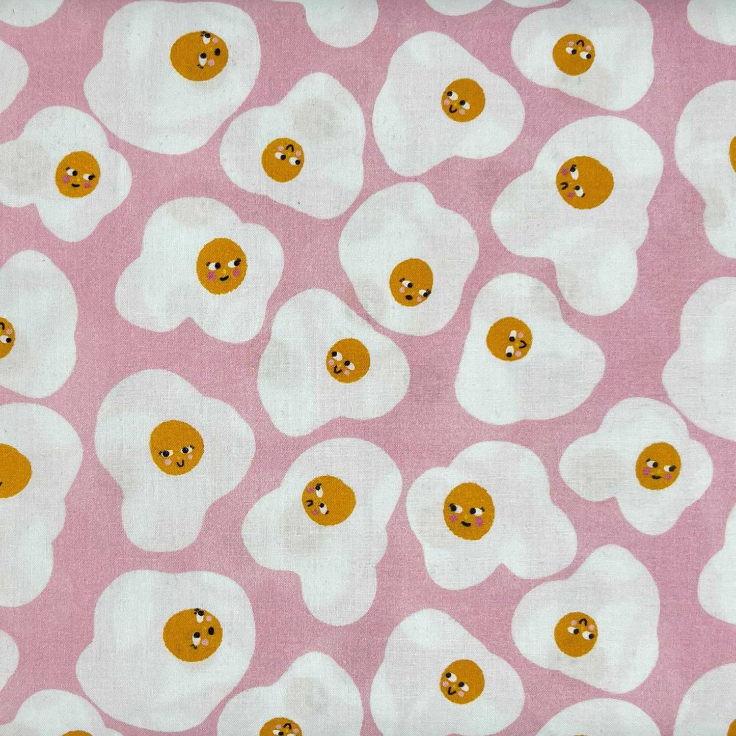 Tessuto a fantasia con uova all'occhio di bue su fondo rosa
