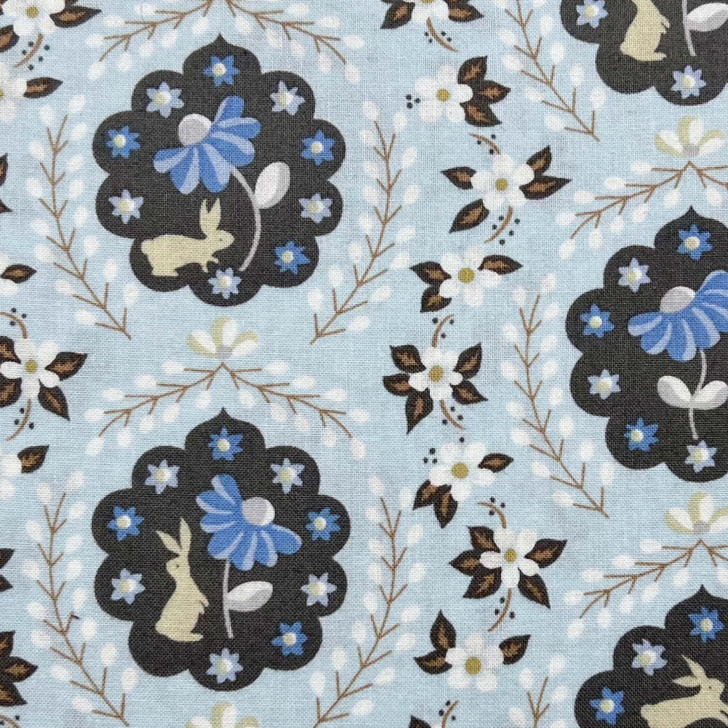 Tessuto a fantasia con coniglietti e fiori su sfondo azzurro